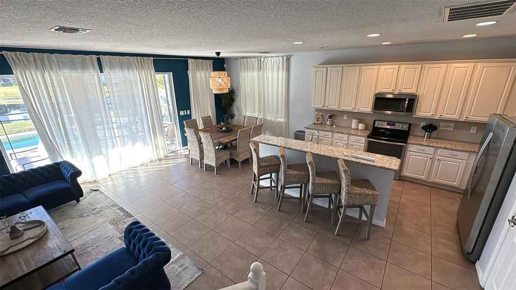 4445 Shiva Loop Kissimmee, FL 34746 - Photo 25 of 33 a kitchen with stainless steel appliances granite countertop a stove top oven a sink a dining table and chairs with wooden floor