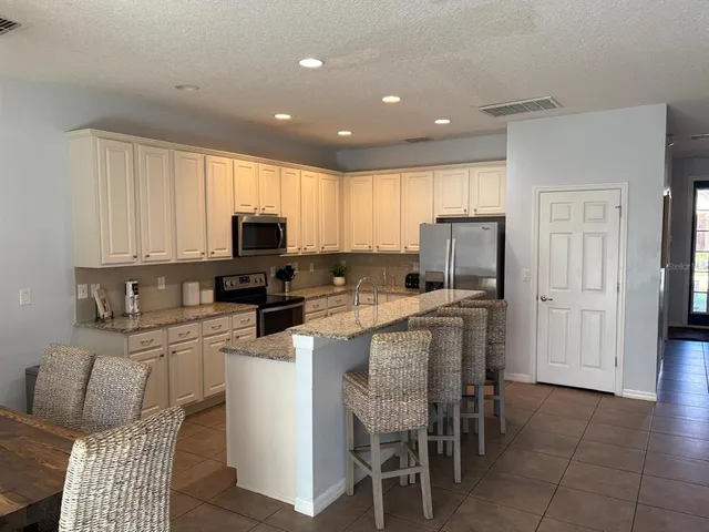 a kitchen with stainless steel appliances granite countertop a stove a sink a microwave a refrigerator and cabinets