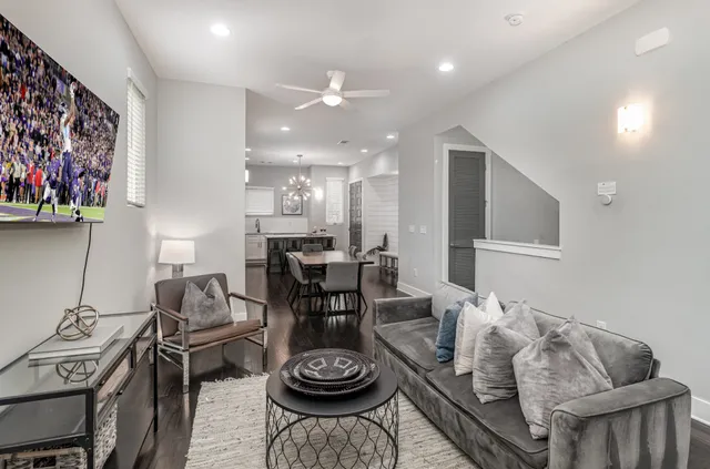 a living room with furniture and a dining table with wooden floor