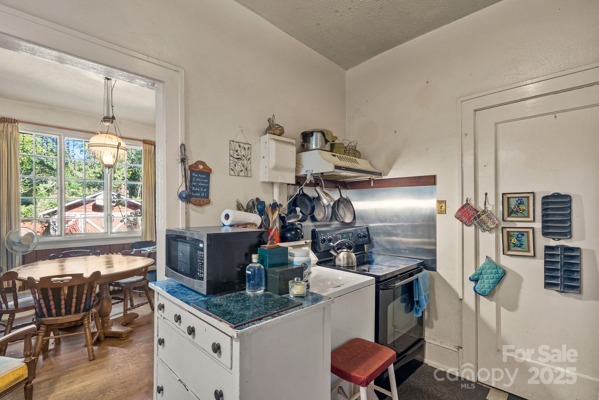 414 Beaucatcher Road Asheville, NC 28805 - Photo 12 of 34 a kitchen with stainless steel appliances kitchen island granite countertop a table chairs in it and wooden floors