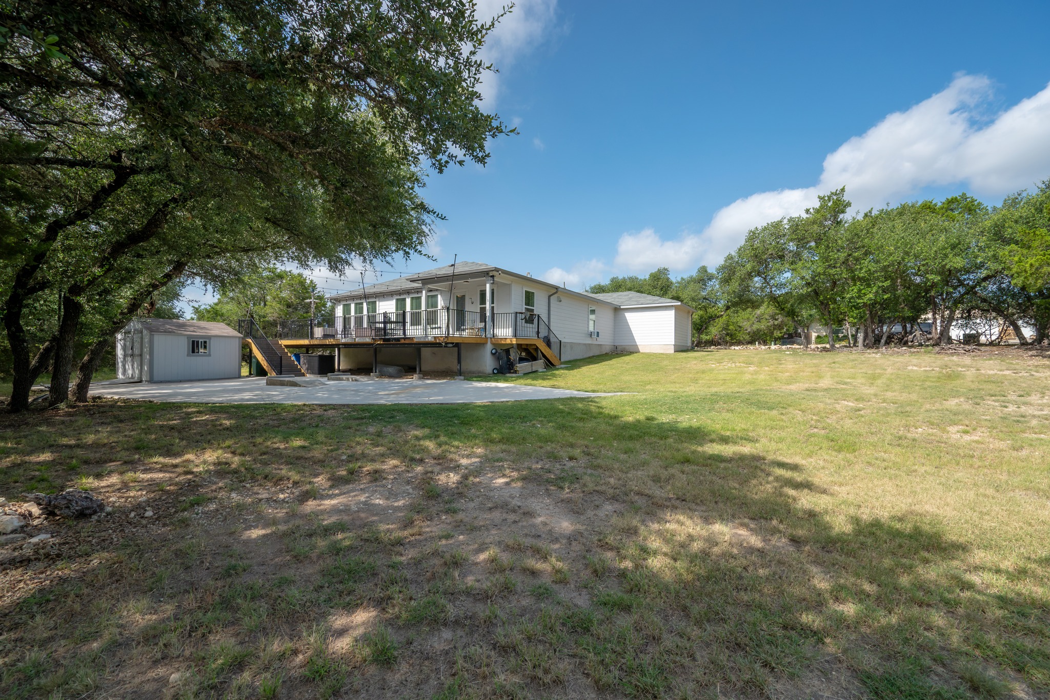 21006 Santa Rosa Avenue Lago Vista, TX 78645 - Photo 22 of 26 A spacious backyard awaits, featuring a wide deck perfect for outdoor enjoyment and a handy shed.