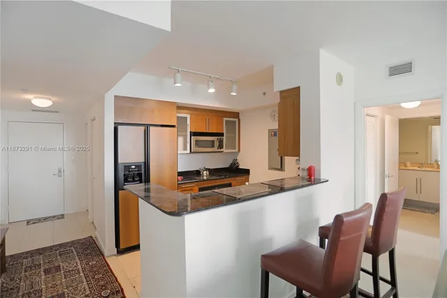 a kitchen with stainless steel appliances granite countertop a sink and a refrigerator
