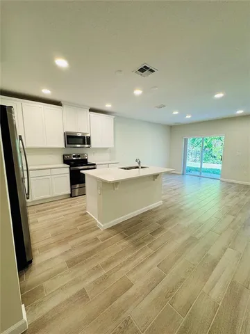 a large kitchen with stainless steel appliances granite countertop a sink and cabinets