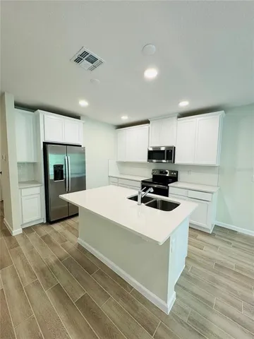 a kitchen with kitchen island a stove a refrigerator and a sink with wooden floor