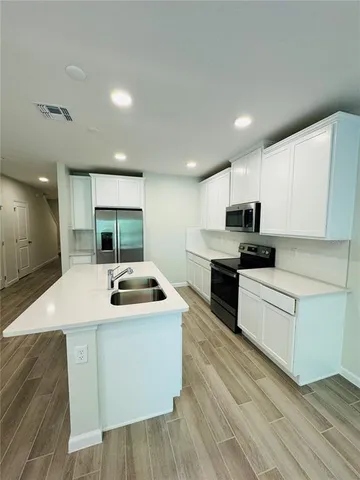 a kitchen with stainless steel appliances granite countertop a sink and white cabinets