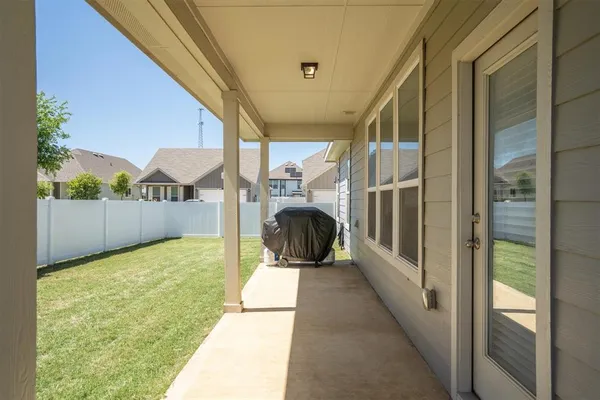a porch with a table and chairs next to a yard