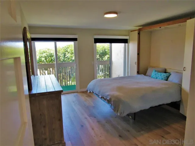 a bedroom with a bed a window and wooden floor