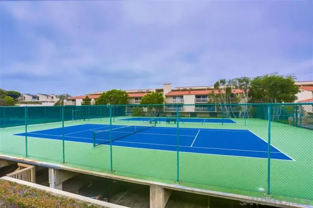 a view of a tennis ground with large trees