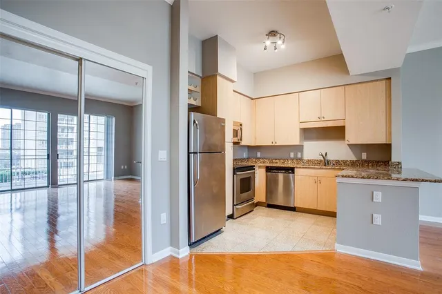a kitchen with granite countertop a refrigerator a sink and white cabinets