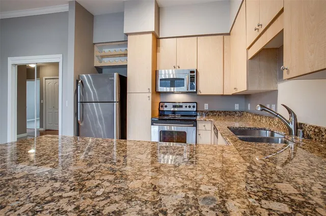 a kitchen with stainless steel appliances granite countertop a refrigerator a stove and a sink with wooden floor