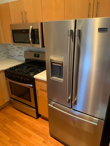 a kitchen with stainless steel appliances granite countertop a refrigerator a stove and a microwave with wooden floor