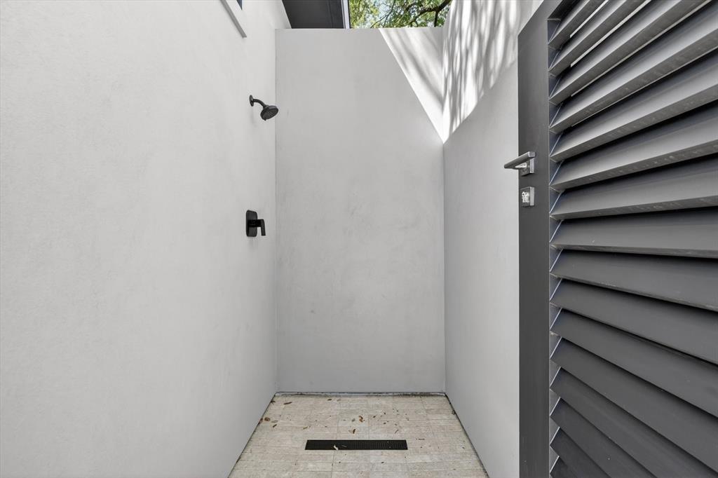 11028 Edgemere Road Dallas, TX 75230 - Photo 39 of 40 Outdoor shower featuring matte black fixtures, light-toned tile flooring with a linear drain, and privacy walls