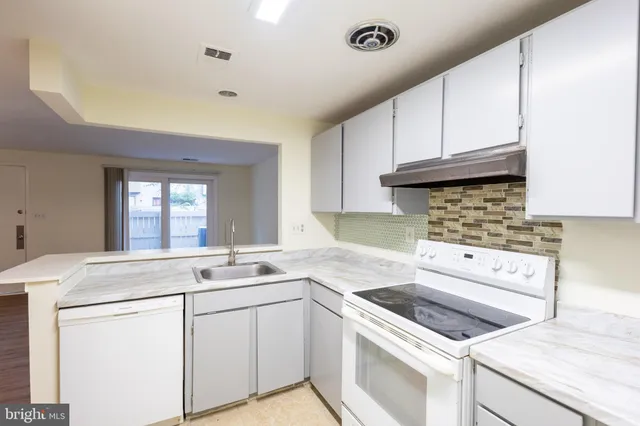 a kitchen with granite countertop white cabinets sink and white appliances