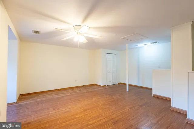 an empty room with wooden floor fan and windows