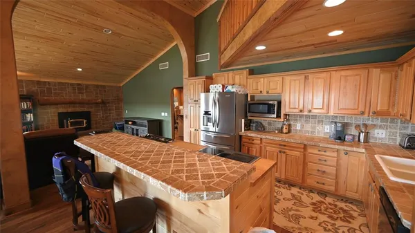 a kitchen with stainless steel appliances kitchen island granite countertop a sink refrigerator dining table and chairs