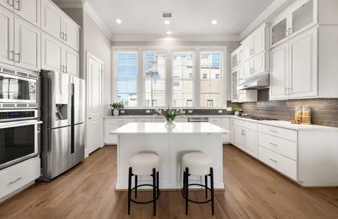 a kitchen with stainless steel appliances granite countertop a table chairs refrigerator and cabinets