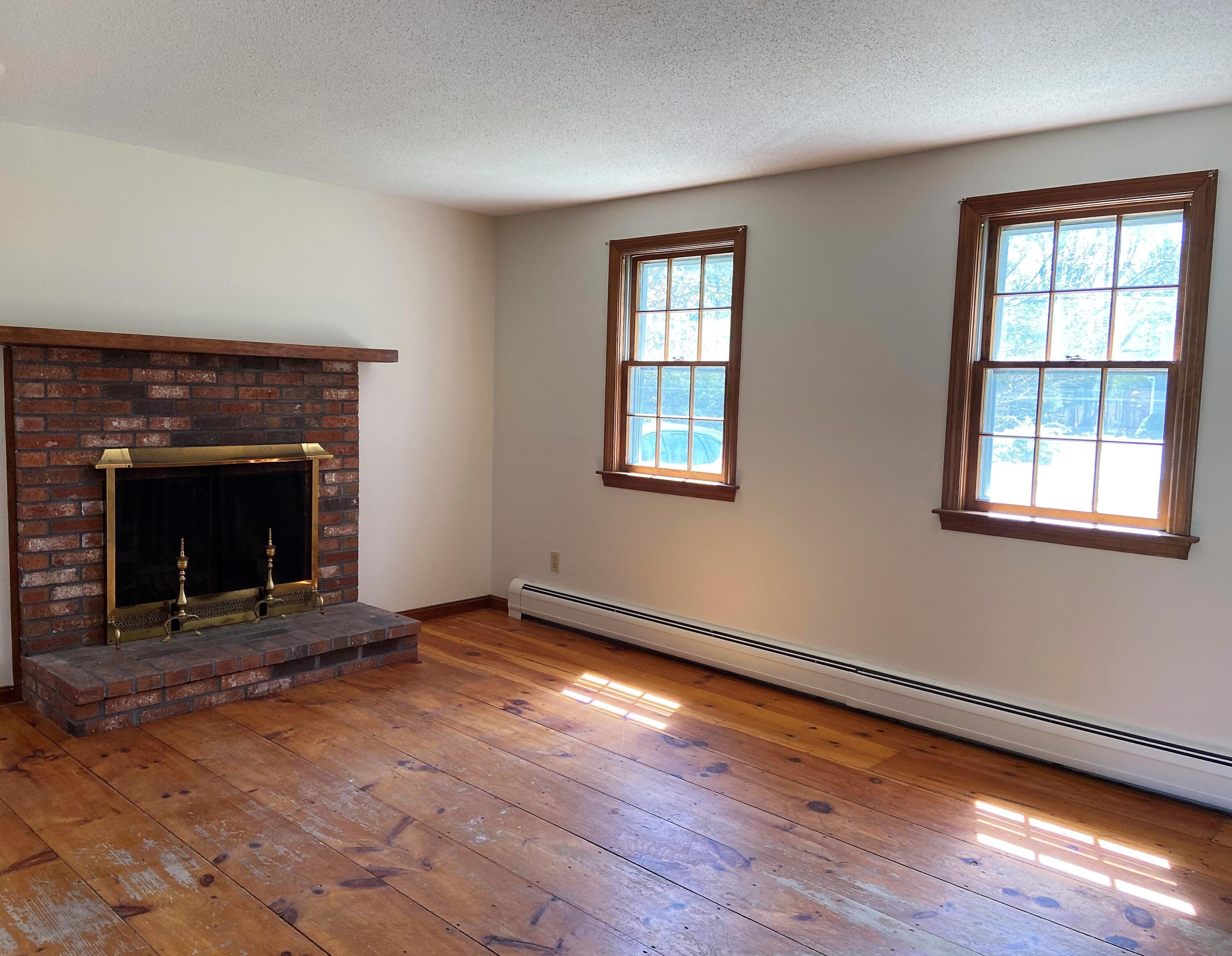 170 Taramac Road Centerville, MA 02632 - Photo 3 of 20 an empty room with wooden floor fireplace and windows