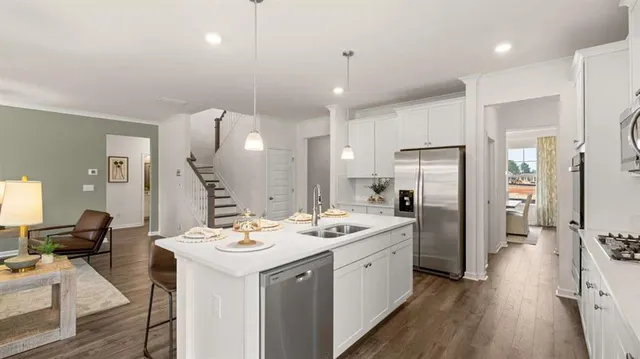 a kitchen with stainless steel appliances granite countertop a refrigerator and a white cabinets