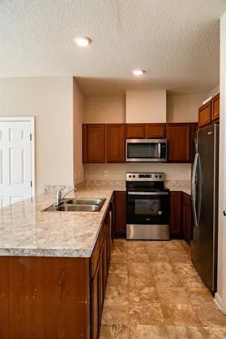 a kitchen with stainless steel appliances granite countertop a stove refrigerator and microwave