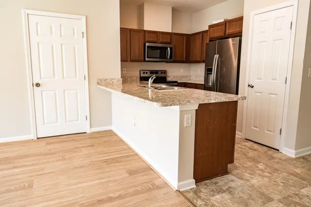 a kitchen with kitchen island a refrigerator and a stove top oven
