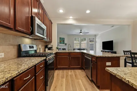 a kitchen with stainless steel appliances granite countertop a stove a sink a microwave a refrigerator and cabinets