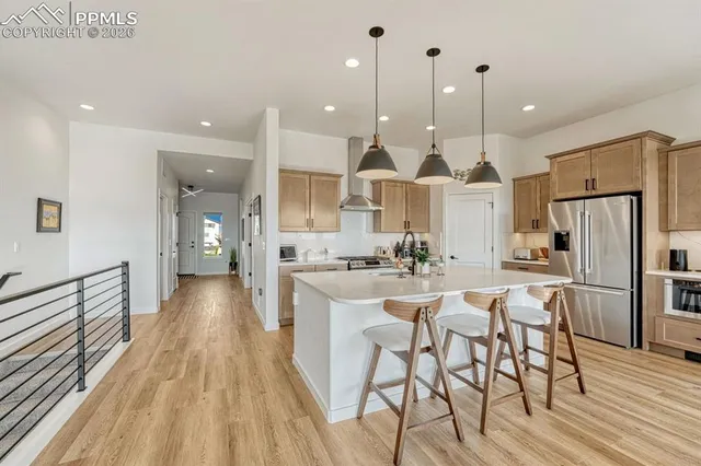 a kitchen with stainless steel appliances kitchen island granite countertop a table chairs refrigerator and sink