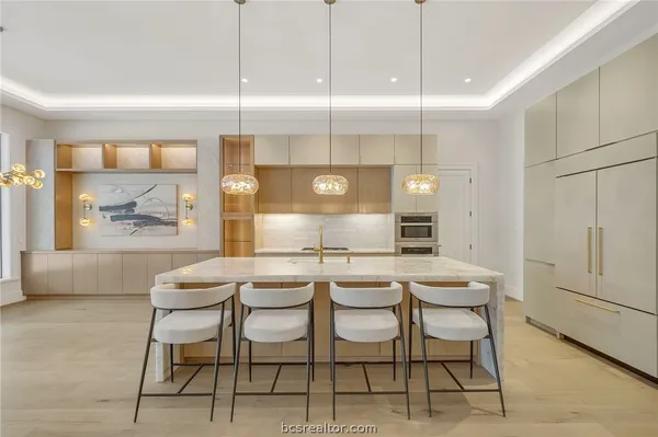 a large kitchen with kitchen island a stove a sink a center island and wooden floor