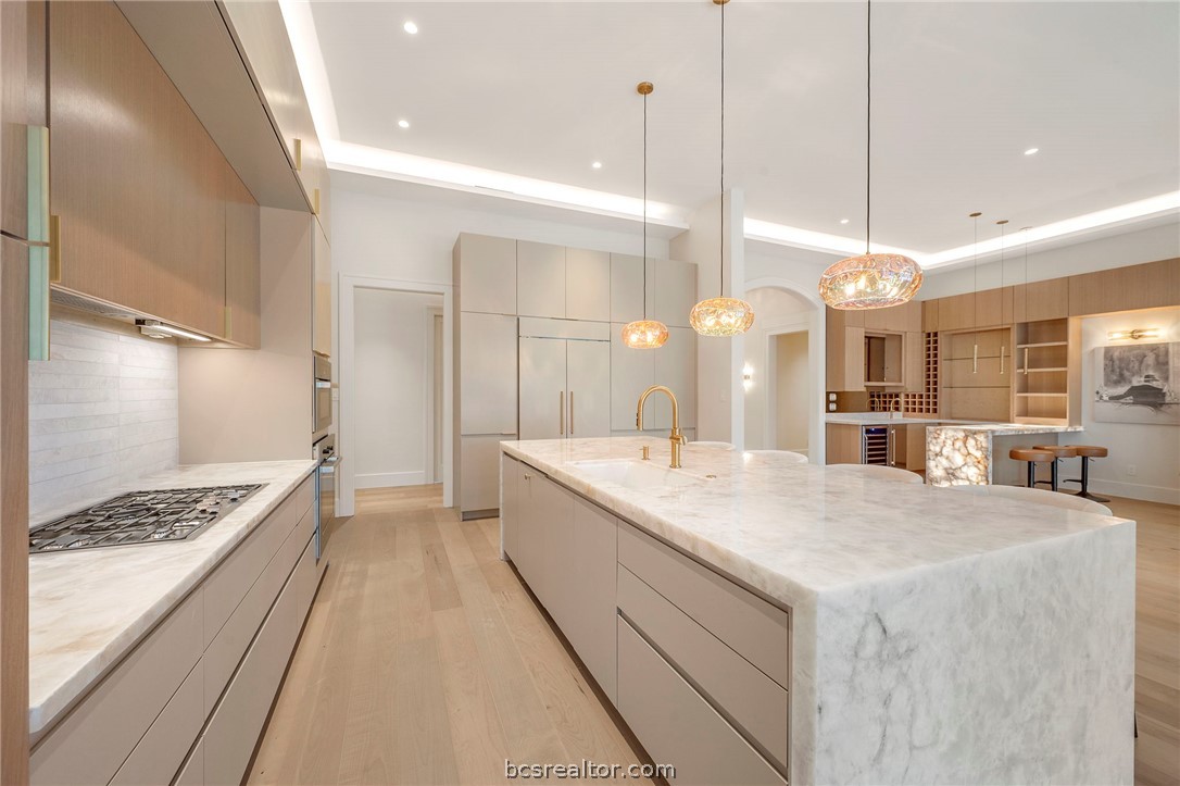 4212 Tuscany Court Bryan, TX 77802 - Photo 12 of 41 a large kitchen with kitchen island a stove a sink a center island and wooden floor