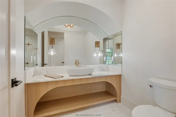 an empty room with windows and view of kitchen