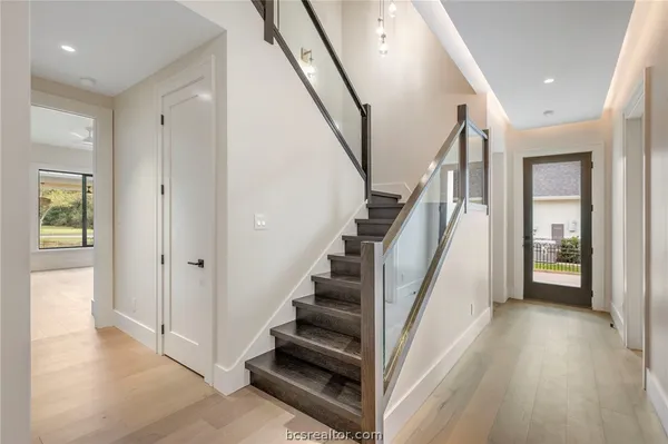 a view of an empty room with wooden floor and a bathroom