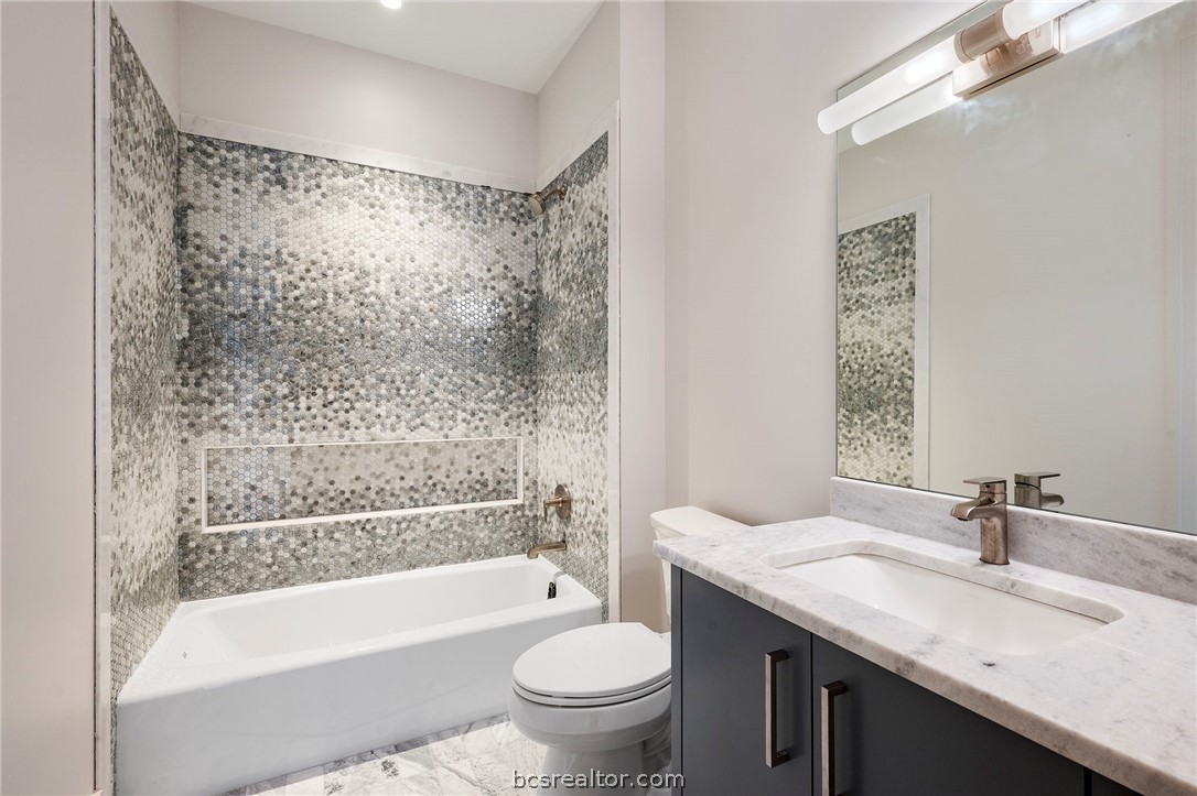 4212 Tuscany Court Bryan, TX 77802 - Photo 31 of 41 a bathroom with a granite countertop sink a toilet a mirror a bathtub and shower
