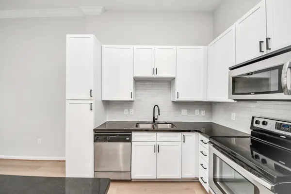 a kitchen with a sink a chandelier stainless steel appliances and wooden floor