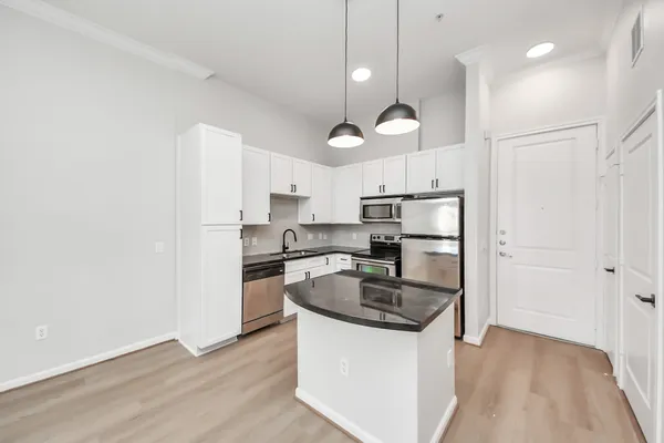 a kitchen with stainless steel appliances granite countertop a sink a stove a refrigerator and island with wooden floor