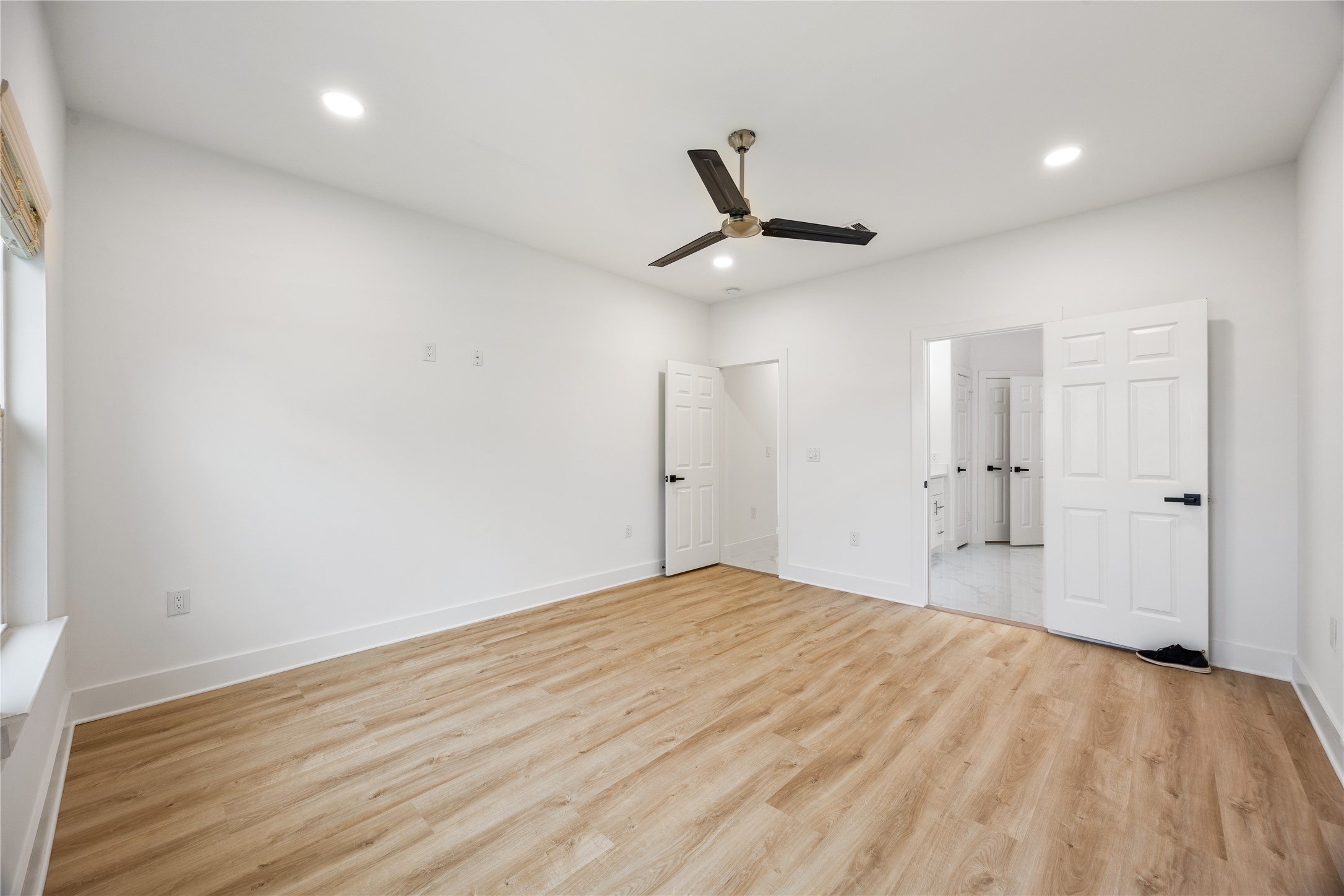 1121 Austin Street Rosenberg, TX 77471 - Photo 26 of 44 This bright, spacious room features luxury vinyl flooring, fresh white walls, and a modern ceiling fan. It includes two doors leading to a closet and a bathroom, providing convenience and functionality.