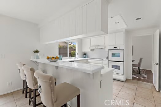 8 Caraway Irvine, CA 92604 - Photo 11 of 33 a kitchen with white cabinets and chairs