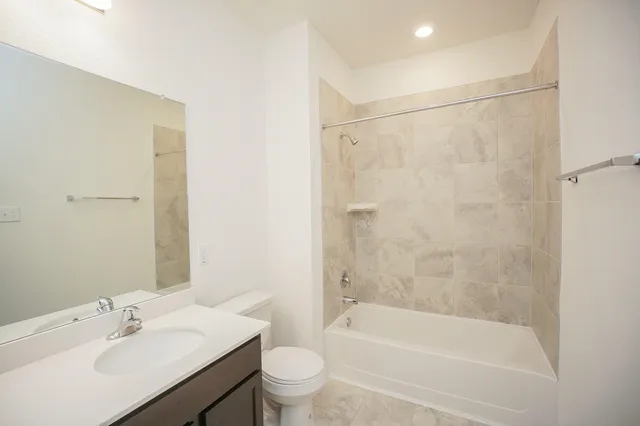 a bathroom with a bathtub shower sink vanity and toilet