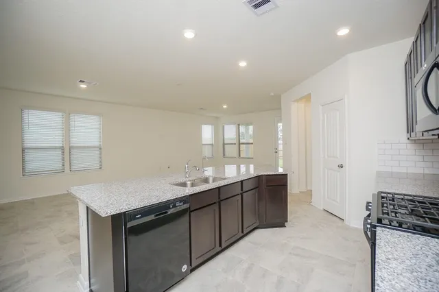 a kitchen with granite countertop stainless steel appliances a sink stove and cabinets