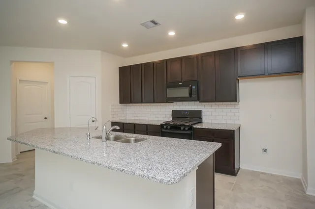 a large kitchen with stainless steel appliances granite countertop a sink a stove and a microwave oven