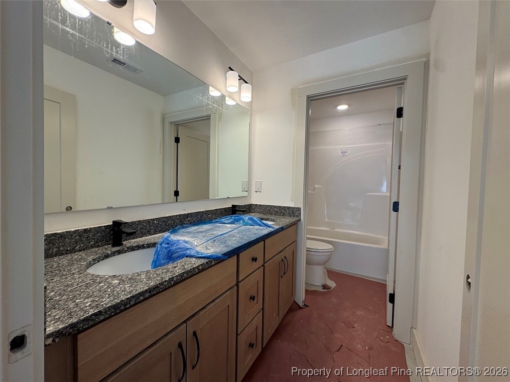 9844 Rockfish Road Raeford, NC 28376 - Photo 12 of 15 a bathroom with a granite countertop sink a toilet a large mirror and shower