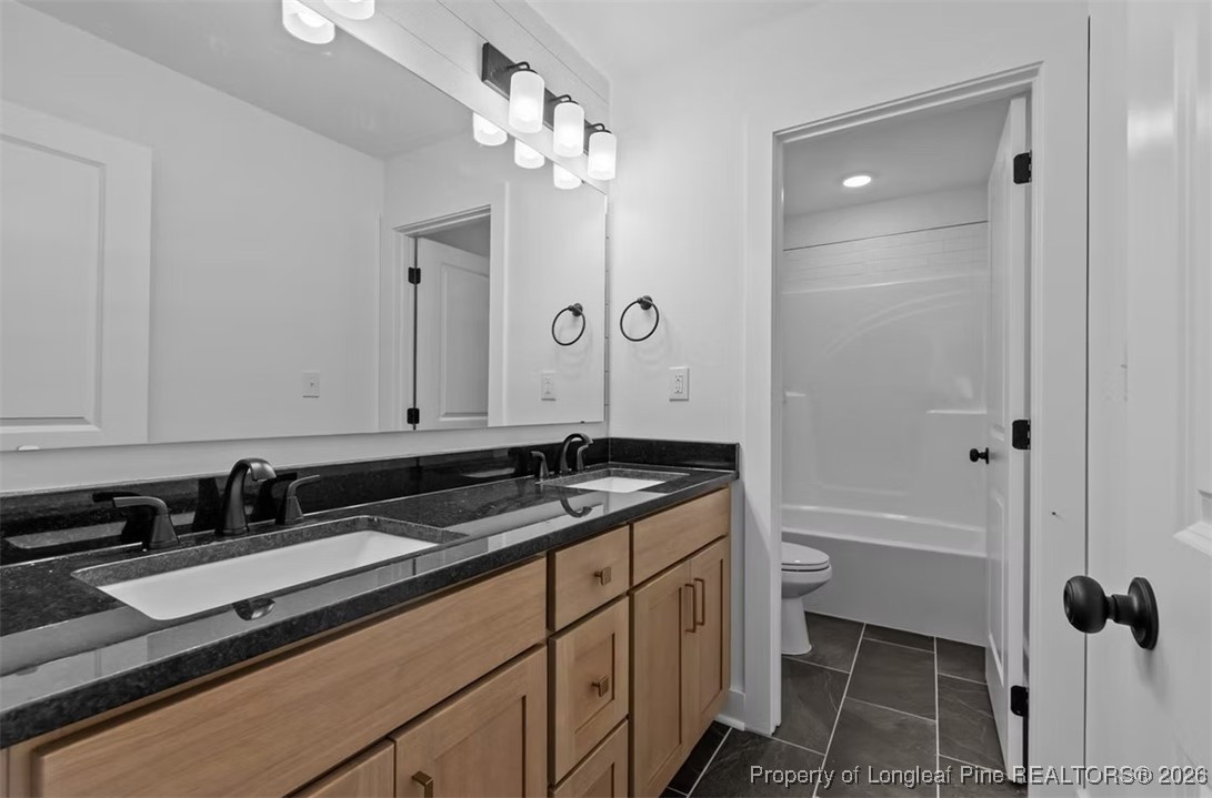 9844 Rockfish Road Raeford, NC 28376 - Photo 15 of 32 a bathroom with a granite countertop sink a toilet a mirror and shower