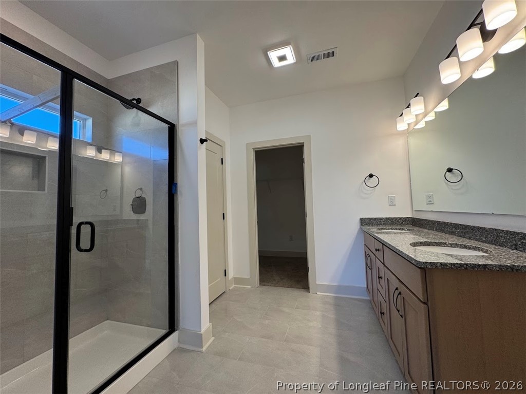 9844 Rockfish Road Raeford, NC 28376 - Photo 24 of 32 a bathroom with a granite countertop sink a mirror and shower