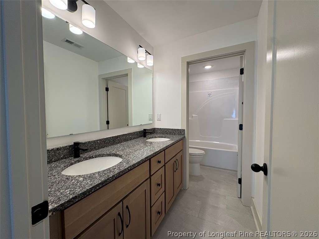 9844 Rockfish Road Raeford, NC 28376 - Photo 26 of 32 a bathroom with a granite countertop double vanity sink a mirror and a shower