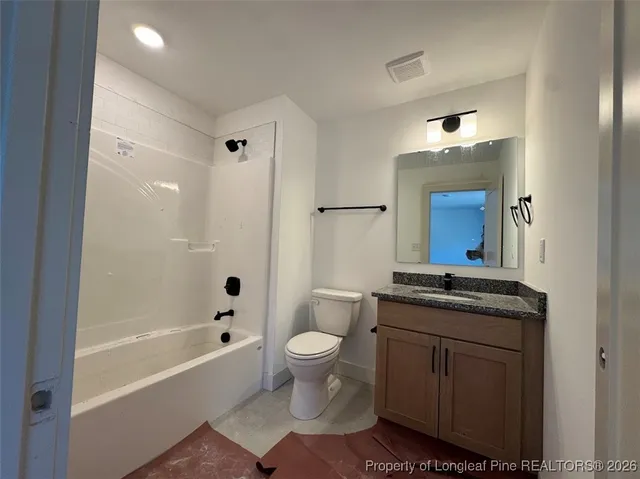 a bathroom with a granite countertop sink a toilet a mirror a bathtub and shower