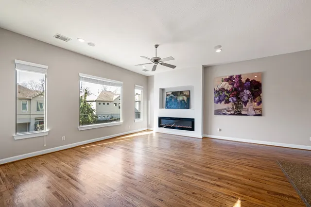 a view of an empty room with a window and wooden floor