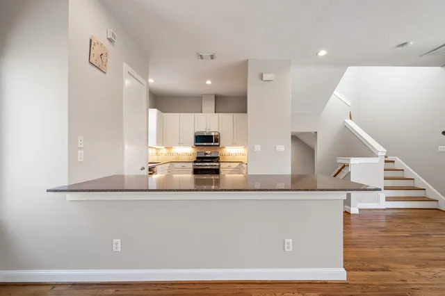 a large white kitchen with wooden floor and stainless steel appliances