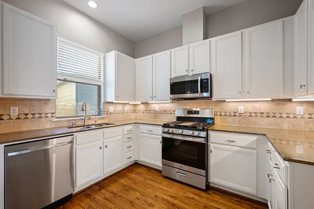 a kitchen with granite countertop white cabinets and white appliances