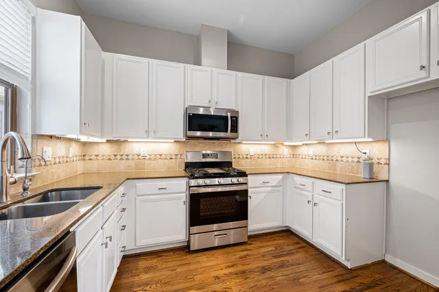 a kitchen with granite countertop a stove sink and cabinets