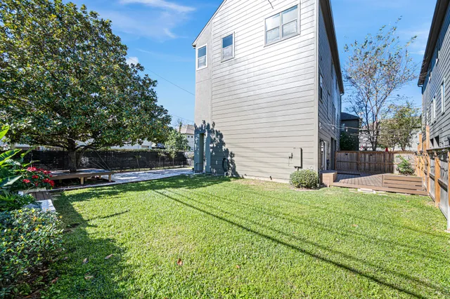 a view of backyard with wooden fence and large trees