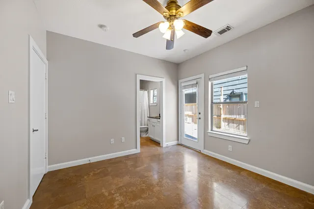 an empty room with chandelier fan and windows