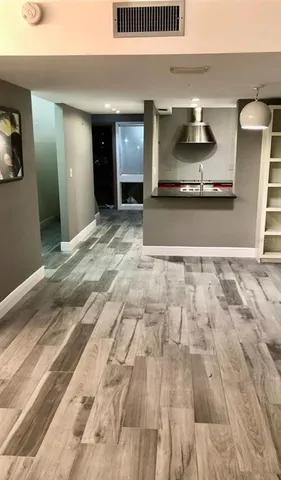 a view of a hallway to room with wooden floor